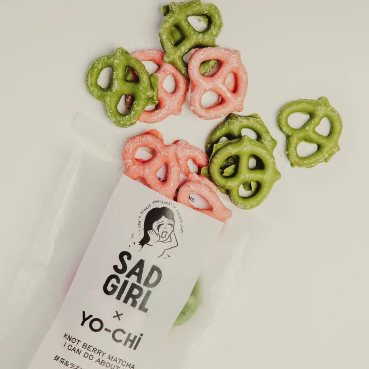 Colorful pretzels next to a 'Sad Girl' branded product on a light background